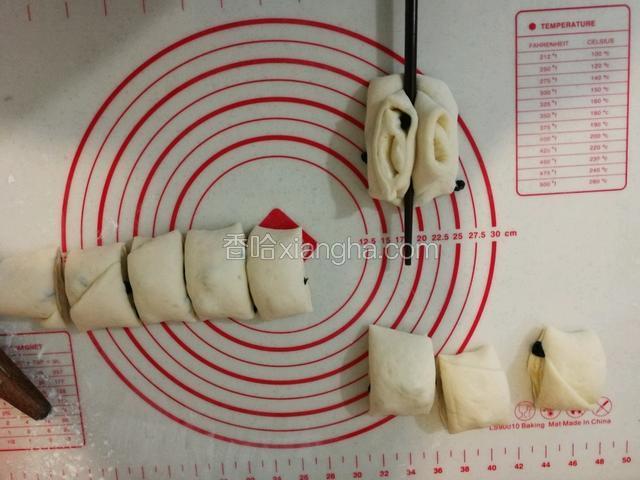 把面饼从下向上卷成卷，用硬刮刀切成10份，然后两个上下叠加起来。如图所示，用筷子在叠加的面团中间向下压下去，然后抽出筷子，用手捏住上下两端同时向下折去并把两端捏紧，放在模具中。