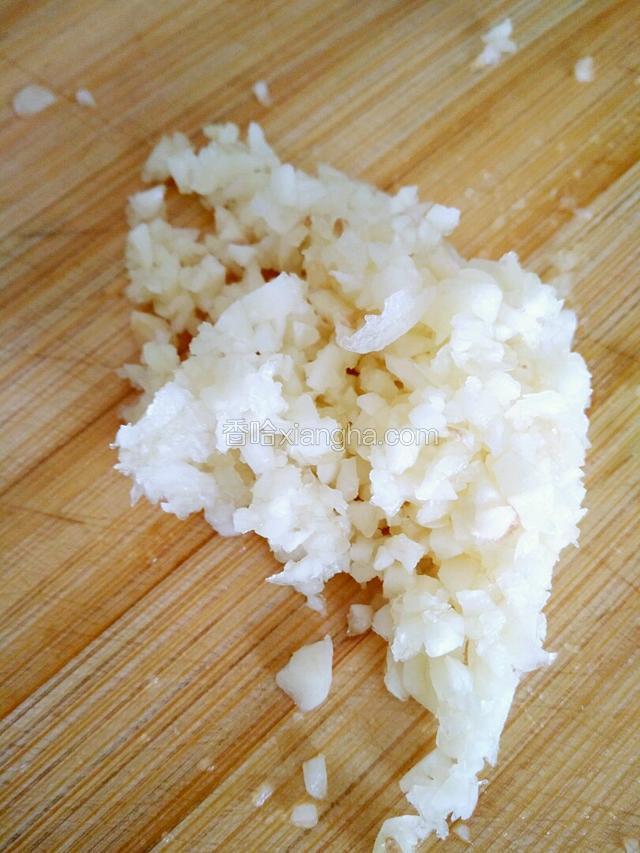 掰几个蒜瓣，用刀拍扁剁成蒜末。