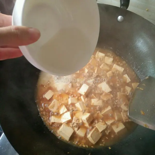 加入适量清水（不要没过豆腐）煮开后第一次加水淀粉，加入一勺白糖和少许盐，稍煮一会再加入第二次水淀粉煮一分钟（要翻动一下），出锅前加一勺辣椒油