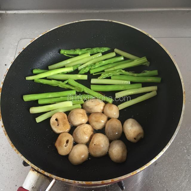 醒牛排的同时，将芦笋和菇倒入煎牛排的锅中，小火慢烤