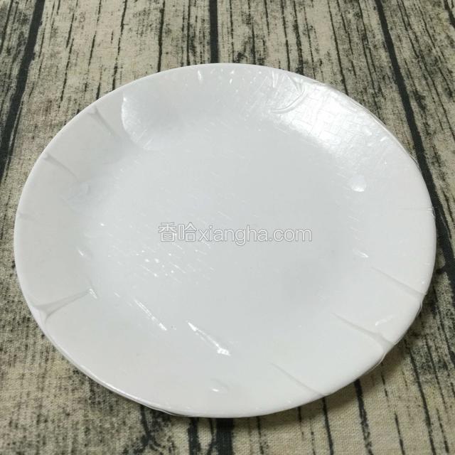 准备好一个干净盘子，
把浸泡好的春卷皮平摊在盘子上。