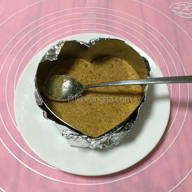 锡纸垫底包住模具。
把搅拌好的饼干碎加进模具里面，
用铁勺子用力~压实压平。
PS：锡纸包不包其实关系不大，因为是整个盘子一起放进冰箱。