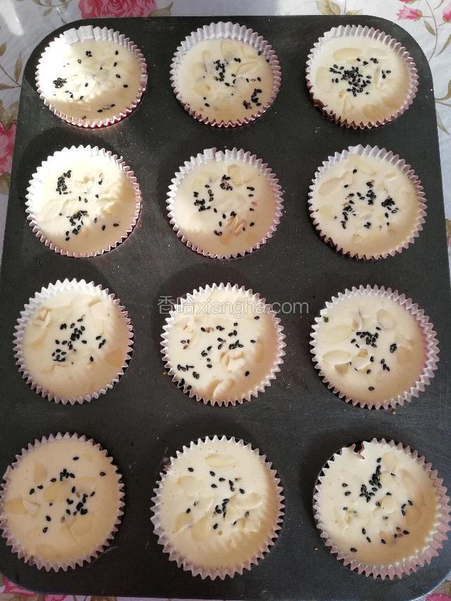 拿起模具震两下震出大气泡，上面撒上黑芝麻和扁桃仁