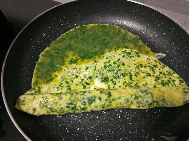 沿一边卷起，留出空位，再倒入1/3蛋液，煎至凝固