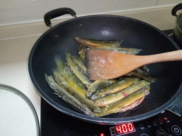 热油锅里放两片生姜，把泥鳅两面煎至半熟，待用。