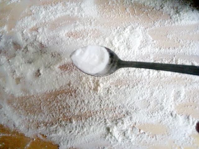 案板上撒一点面粉，放小半勺碱面，用擀面杖擀开和面粉拌匀