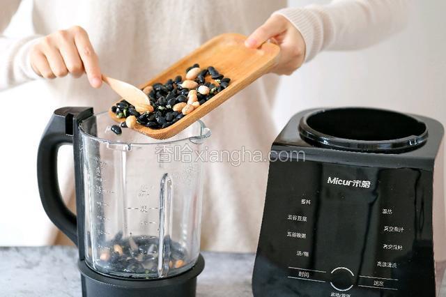 将浸泡好的黑豆和花生放入破壁机的搅拌杯内