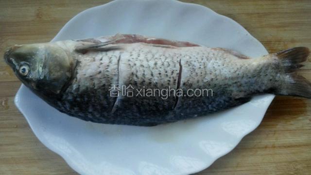先把鱼清洗干净，在鱼身上反正两面各划两刀，撒上盐腌十五分钟。