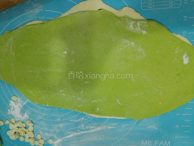 菠菜面团用擀面杖压平后，刷点水，和白面叠一起，用擀面杖压一压