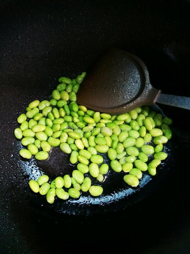锅中倒入适量油，烧到七成热放入毛豆煸炒。