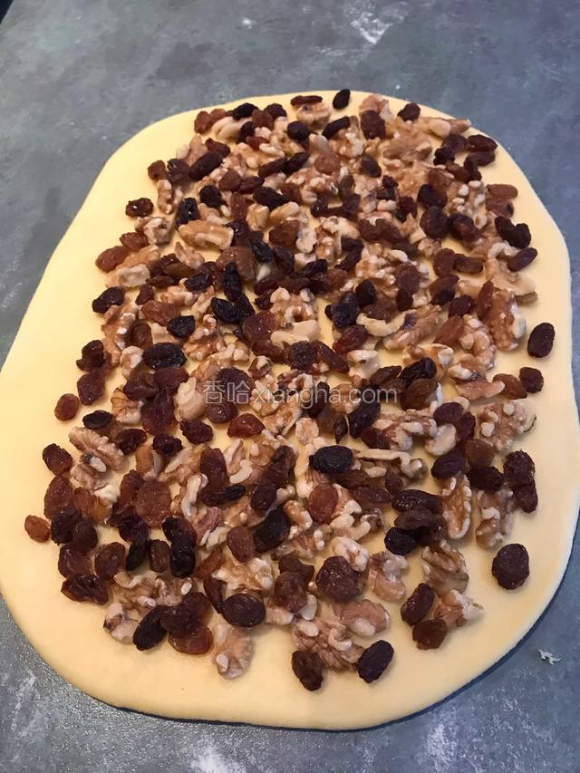 醒好的面团分割成两份，擀成薄点的面皮，铺上果仁