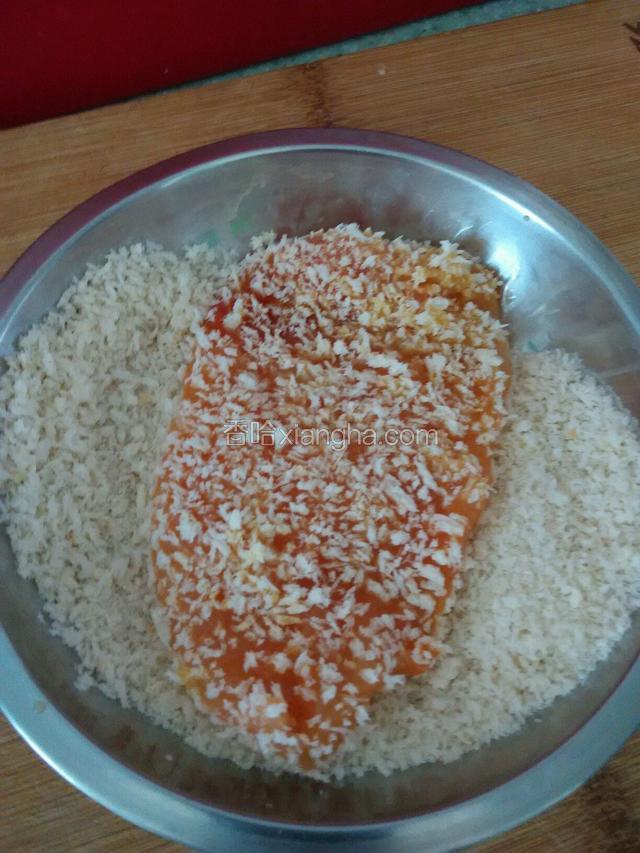 挂上鸡蛋液的鸡排在两面沾上面包糠。
