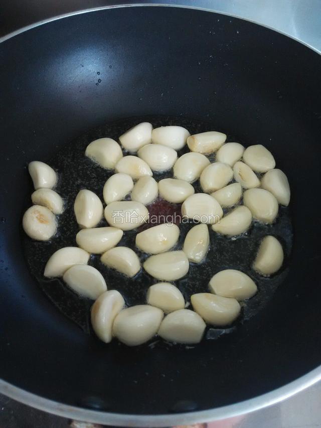 锅上火倒入适量植物油，下入蒜瓣温油中火慢炒。