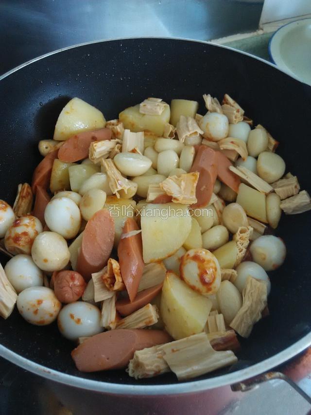 依次将土豆、火腿肠、鹌鹑蛋、腐竹、蒜瓣全部倒入翻炒。