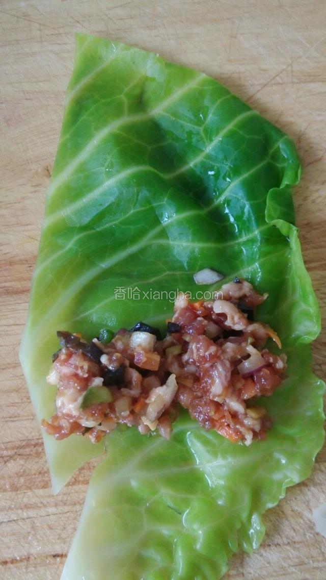 将拌好的肉馅放到圆白菜上卷起来