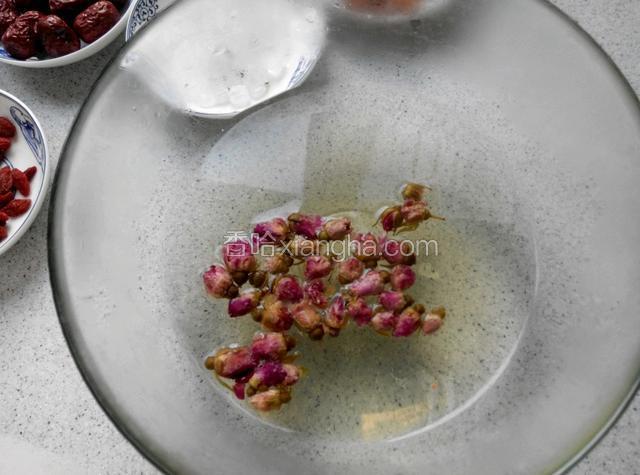 玫瑰花热水泡开，加几块冰糖。糯米淘干净，待玫瑰水凉后将糯米放进去浸泡。