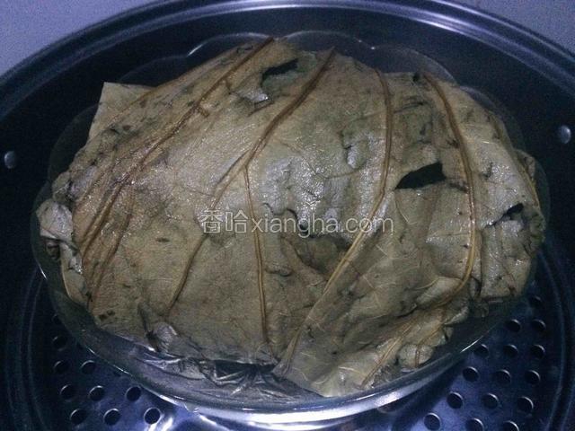 用荷叶包裹腌制好的三黄鸡，放进容器，盖上盖子，防止蒸汽流到里面；