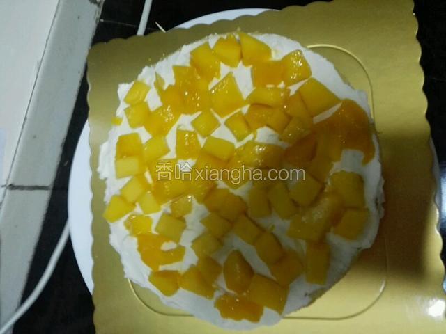 取顶片蛋糕片抹上奶油撒上芒果碎再抹上奶油。取第二片同样抹上奶油撒芒果碎再抹上奶油盖最后一片。要盖平整。