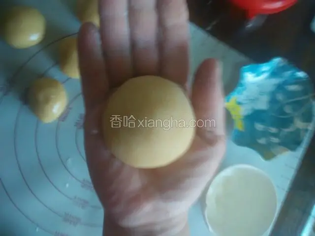 手上沾点干面粉取一个面球放入掌心揉一下，让面团表面沾上薄薄一层干粉（一定是薄薄一层）目的是豆馅和面团能很好的粘在一起，而且也好脱膜。