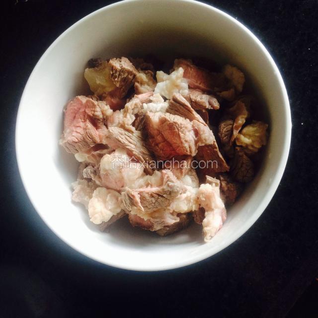 将除去血水的牛肉，用冷水洗一下，切成一块一块的，装入碗里。