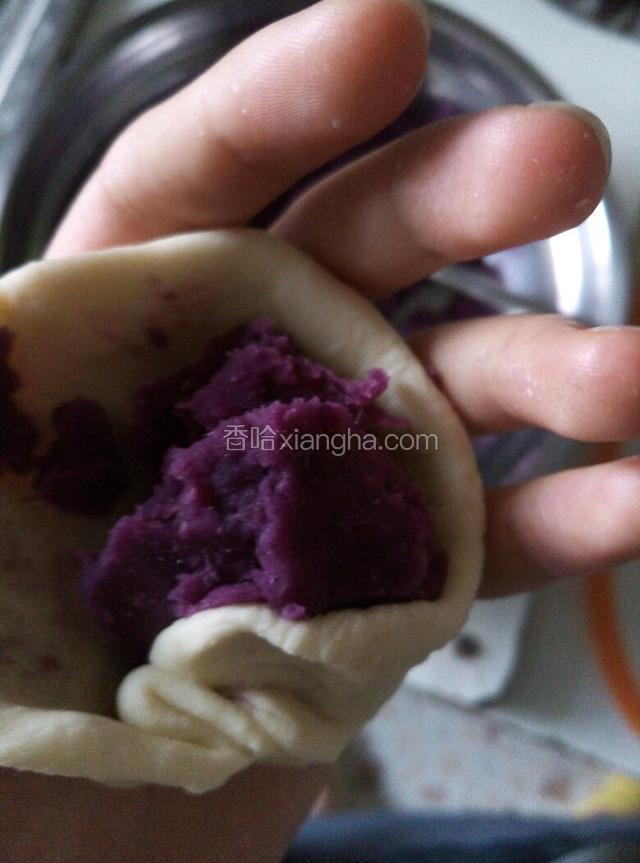 取一个面团压平置于掌心处，夹部分紫薯泥置于上方（多少由你自己定）