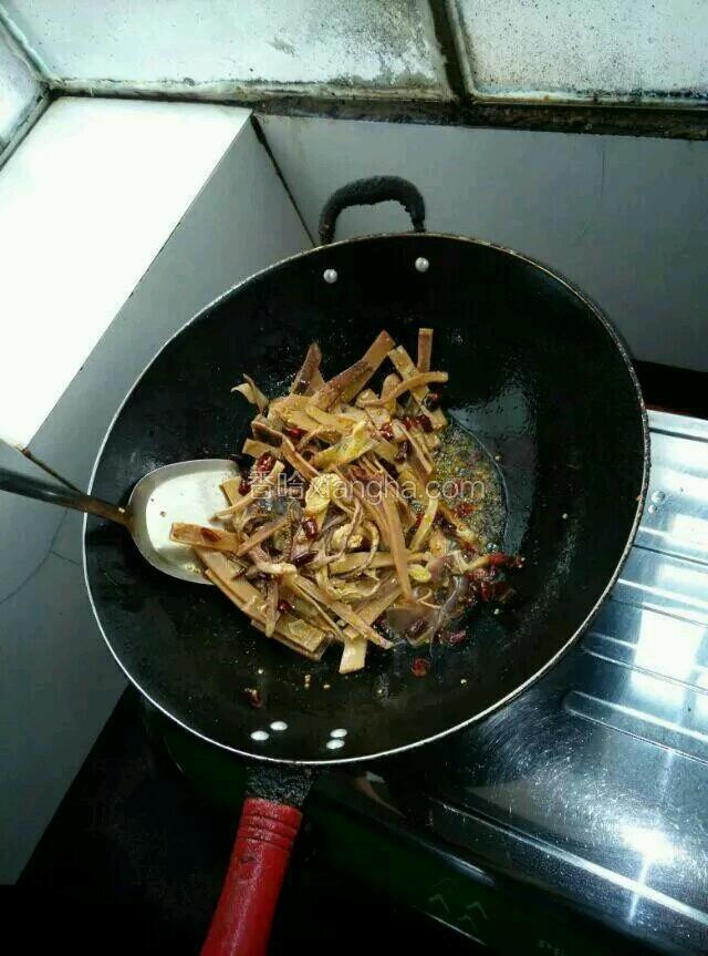 油烧滚烫后放入少许的生姜在油里面，熬一下这会让油更加的香抄出来的菜更加美味，熬好后到入主食鱿鱼干，不停地翻炒，以免炒糊炒的半熟的时候加入干辣椒，盐，继续炒