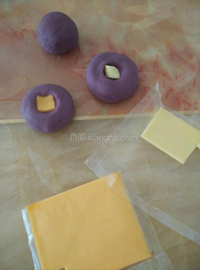 然后按扁，用手在中间按一下，放入芝士或者是奶酪片，然后在把它揉成圆形