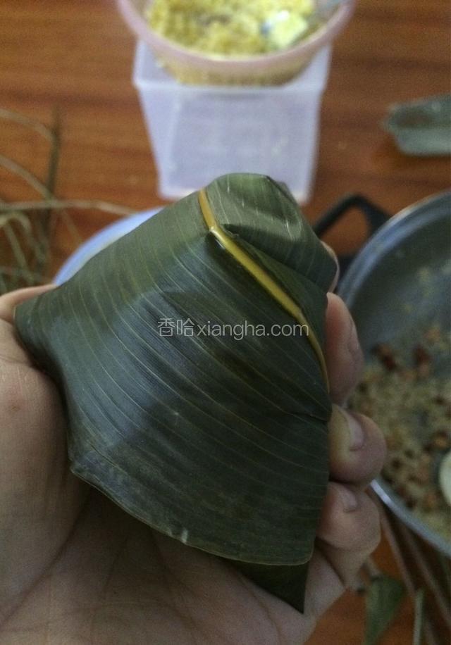 轻轻的把三角形的左边右边折起来，中间长的粽叶往尾端90度角折过，三角形状就出来了…
