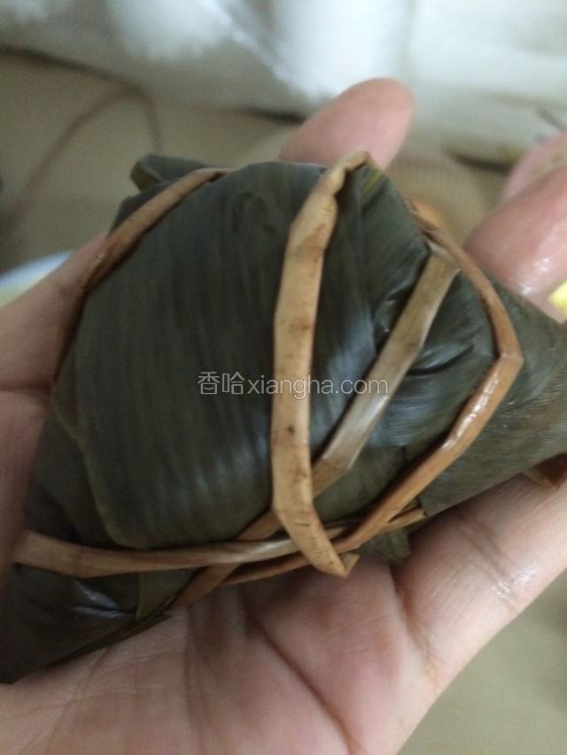 用绳子把三个角包起来，不要太用力，但要用手掌裹住粽子，绕好后打结…