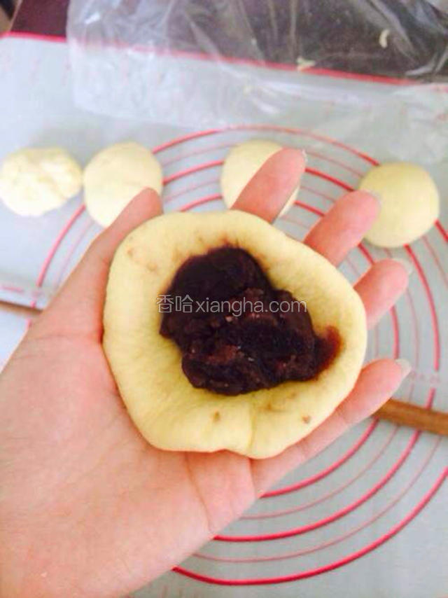 然后包入红豆馅儿，不用太多，适量就好。然后封好口，包好。再在面板上滚一下，呈椭圆形