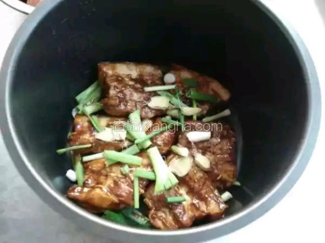 码一层五花肉，再放一层葱段、姜片。