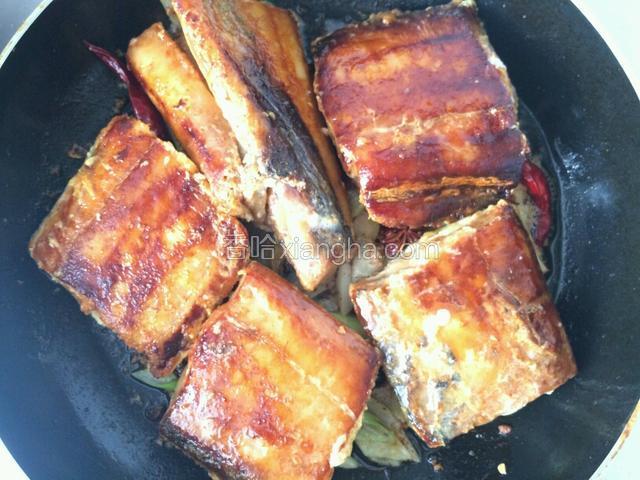 把煸好的调料均匀铺在锅底，把煎好的带鱼段摆在调味料上面；