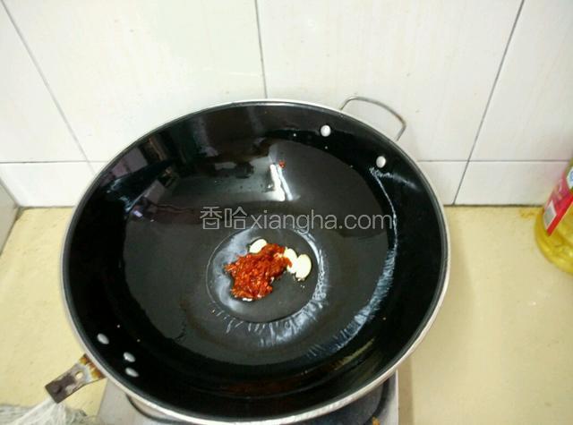 用锅内炸茄子的油，放入蒜粒和豆瓣酱煸炒出香味