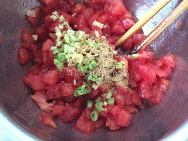 西红柿碎丁里先放1汤匙油拌匀，这一步是为了让西红柿周围形成油膜，减少汤汁的产生。放入姜蒜末和十三香；