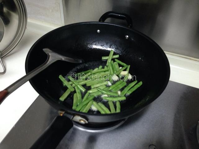 锅内放油，炒香大蒜，然后放豆角炒至变色