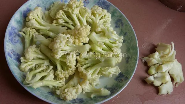 花菜用盐水浸泡二十分钟，用清水洗净，撕小朵。把花菜头也切掉