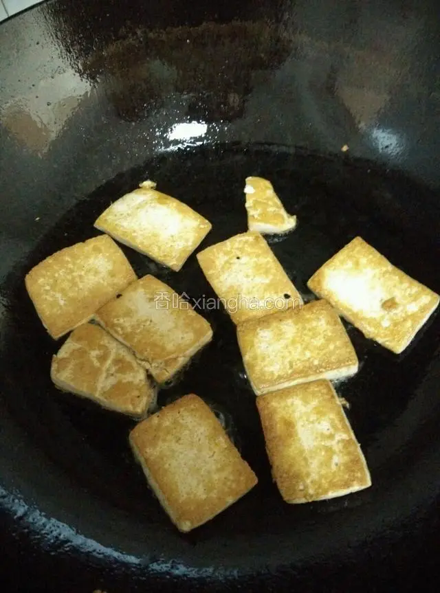 倒少许油在锅中，待油温升高，把切好的豆腐块放入锅中煎。开小火，把豆腐块两面煎至金黄色。然后装盘。
