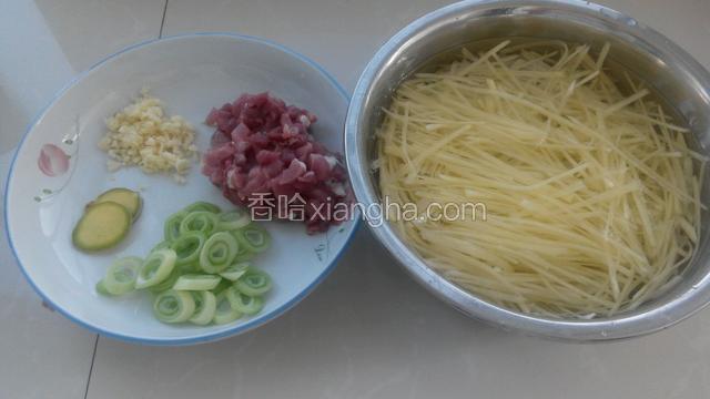 准备好食材，土豆切丝过两遍水直接泡在水中，肉切丁，姜切片，切蒜末和葱花。