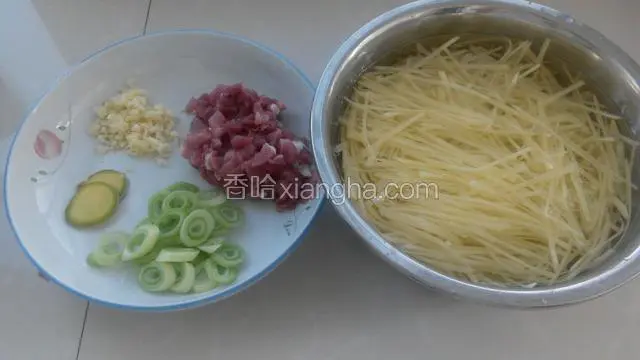 准备好食材，土豆切丝过两遍水直接泡在水中，肉切丁，姜切片，切蒜末和葱花。