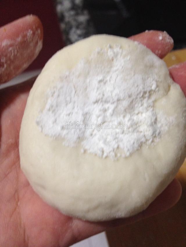 每个剂子分别包一小撮干面粉，包口朝下，压扁擀成小面饼。