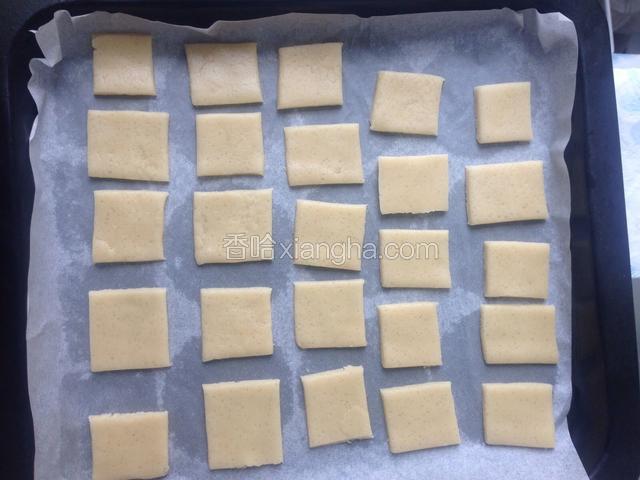 烤箱预热190度。把面团擀成0.3厘米的薄片，切块。放入烤盘。