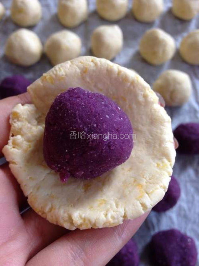 取一小块面团，用手轻轻按扁，再放入紫薯馅，慢慢收口滚成小球。

