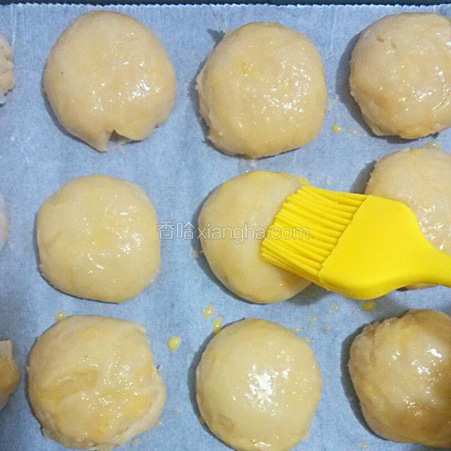 把包好收口朝下的酥饼的入铺好油纸的烤盘里，稍微压煸，刷上蛋黄液