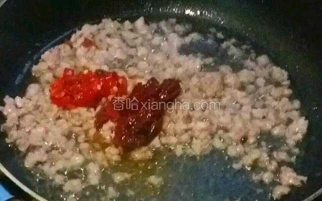 待水分蒸发完后，下入郫县豆瓣炒至出红油后放入泡椒略炒。
