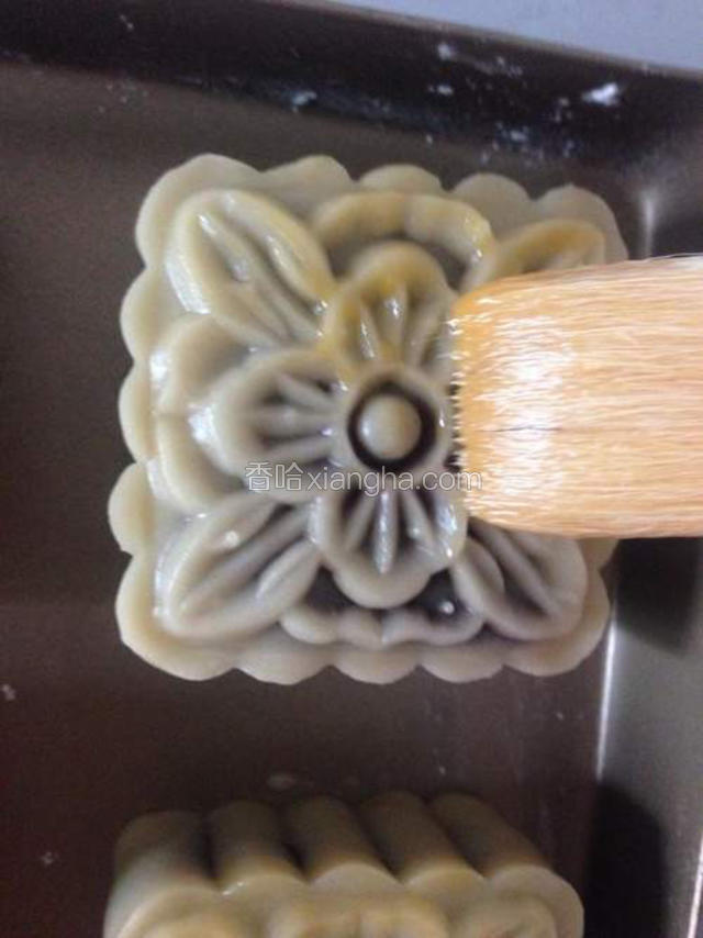 烤箱调温至180度。月饼取出晾五分钟，这期间在表面刷蛋液，注意要用最软的毛刷一点点的刷，千万不要贪多