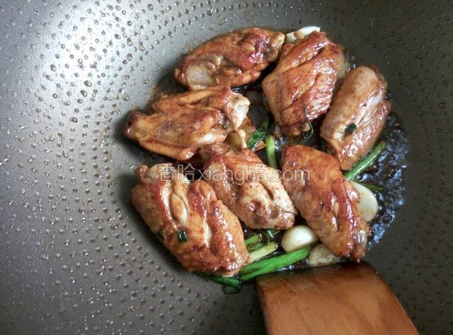 放入葱姜蒜翻炒入味,然后加入两勺生抽、半勺老抽、冰糖3粒、醋半勺、调味粉半勺,翻炒至鸡翅入色