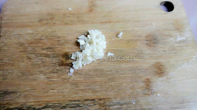 蒜头用刀拍扁，剥掉外壳，切掉头尾，切碎。
