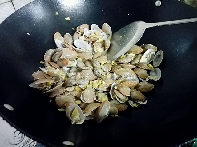 再倒入花甲翻炒，然后放一点点水盖上盖子煮1分钟