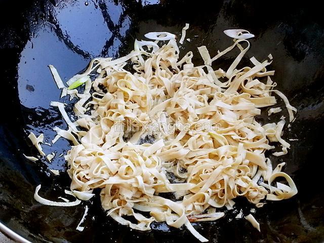 油烧热后下葱段炒香，放入豆腐皮翻炒，加白糖，加适量开水