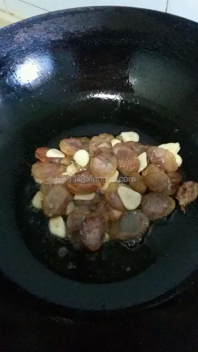 锅热放少许油倒入香肠中火炒至香肠有点卷边时放入蒜片炒出香味
